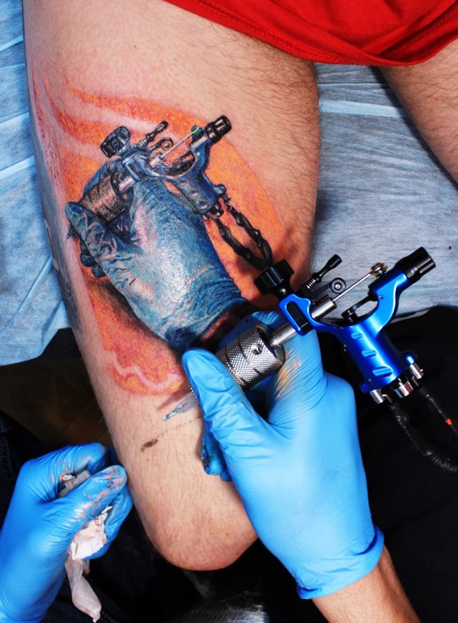 Рука татуировщика с машинкой